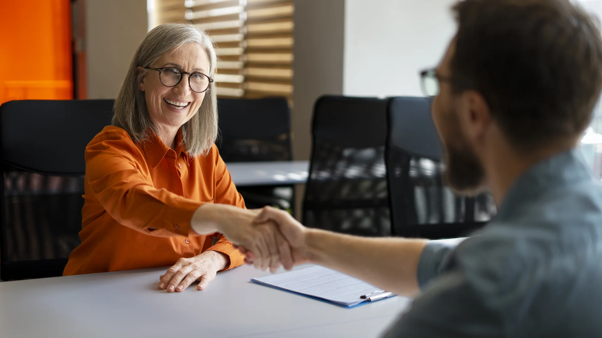 Acquisizione di Clienti 1 Acquisizione di Clienti - due persone che si stringono la mano seduti alla scrivania
